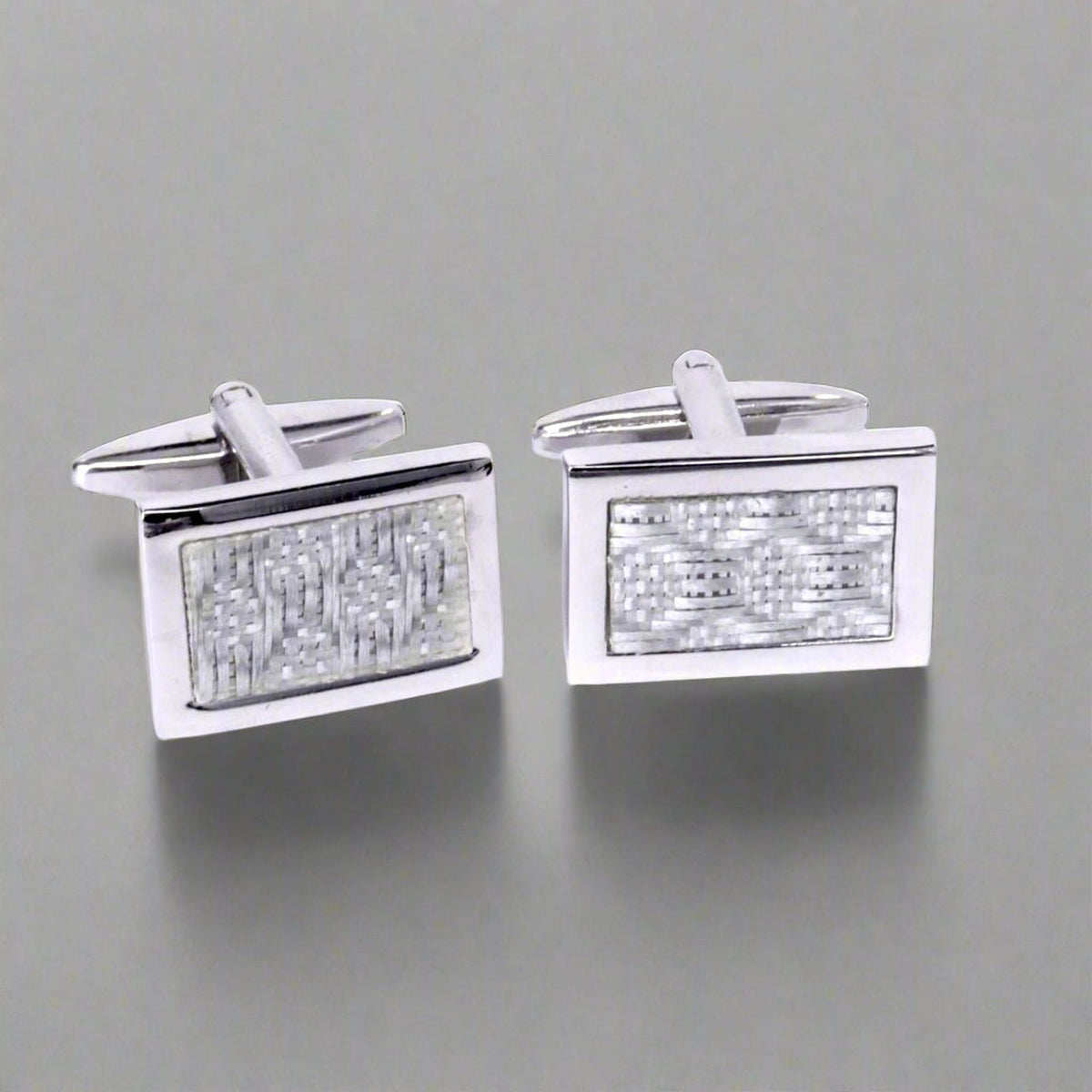 Pair of silver rectangular cufflinks with textured design on a white background