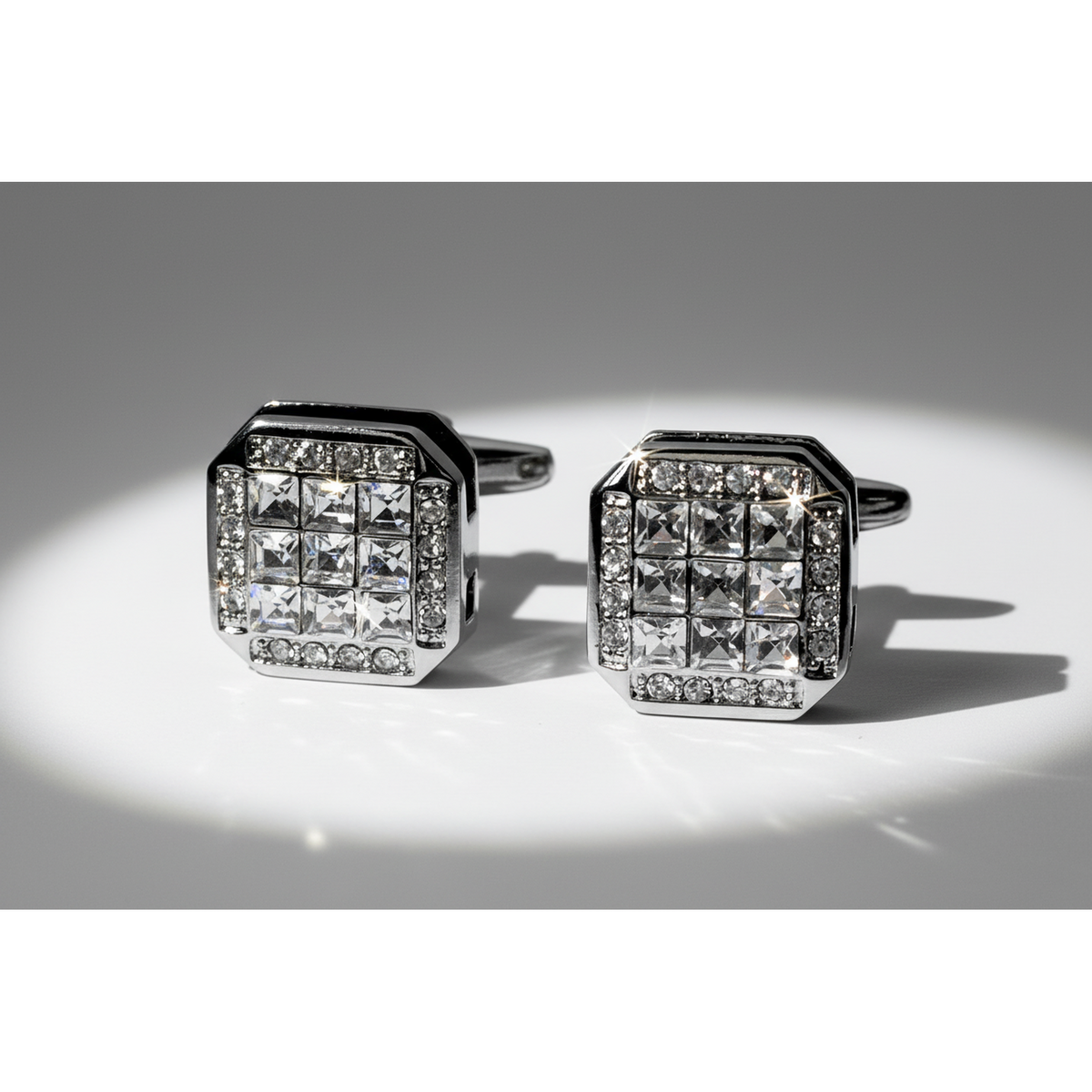 Pair of diamond cufflinks on a reflective surface with a gray background