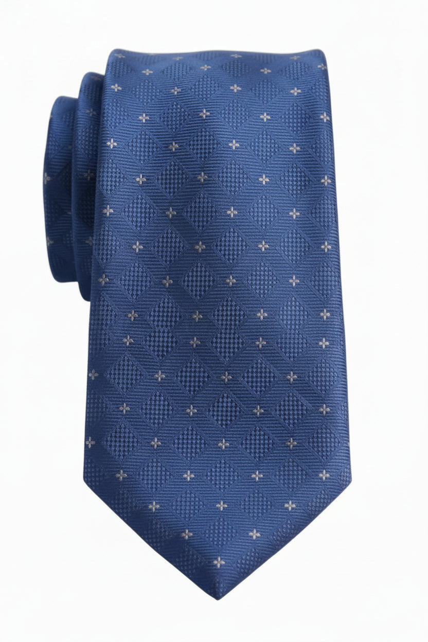 A blue necktie with a textured geometric diamond pattern and small white cross motifs, displayed on a light wood surface.