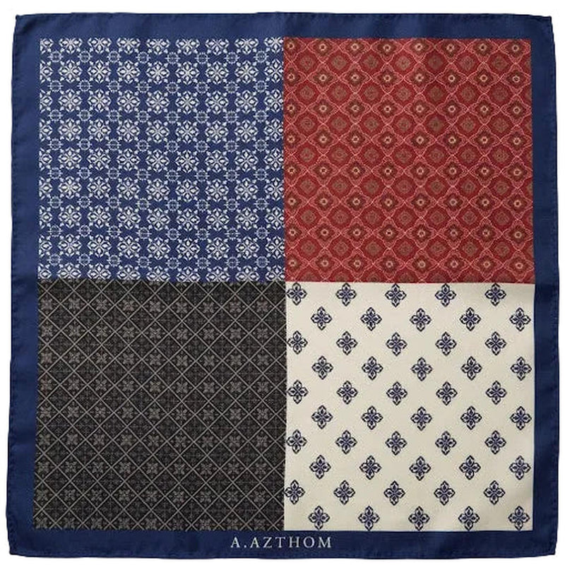 A square silk scarf laid flat on a neutral gray background, featuring a four-quadrant patterned design with a solid navy blue border. The top-left quadrant is navy blue with a white floral lattice pattern, the top-right is red with a gold geometric diamond pattern, the bottom-left is dark gray with a fine gold lattice pattern, and the bottom-right is cream with a navy blue floral lattice pattern.