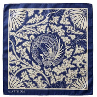 A square silk scarf with a navy blue border and a central dragon motif surrounded by intricate cloud and floral patterns in cream and navy blue. The brand name 'A.