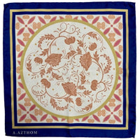 A square silk scarf with a traditional floral pattern, featuring a navy blue border, a gold inner border, and a central cream circle with terracotta-colored botanical motifs. The brand name 'A.
