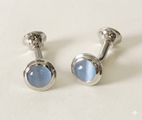 A pair of silver-toned cufflinks with oval light blue cateye, displayed on a clean off-white background.