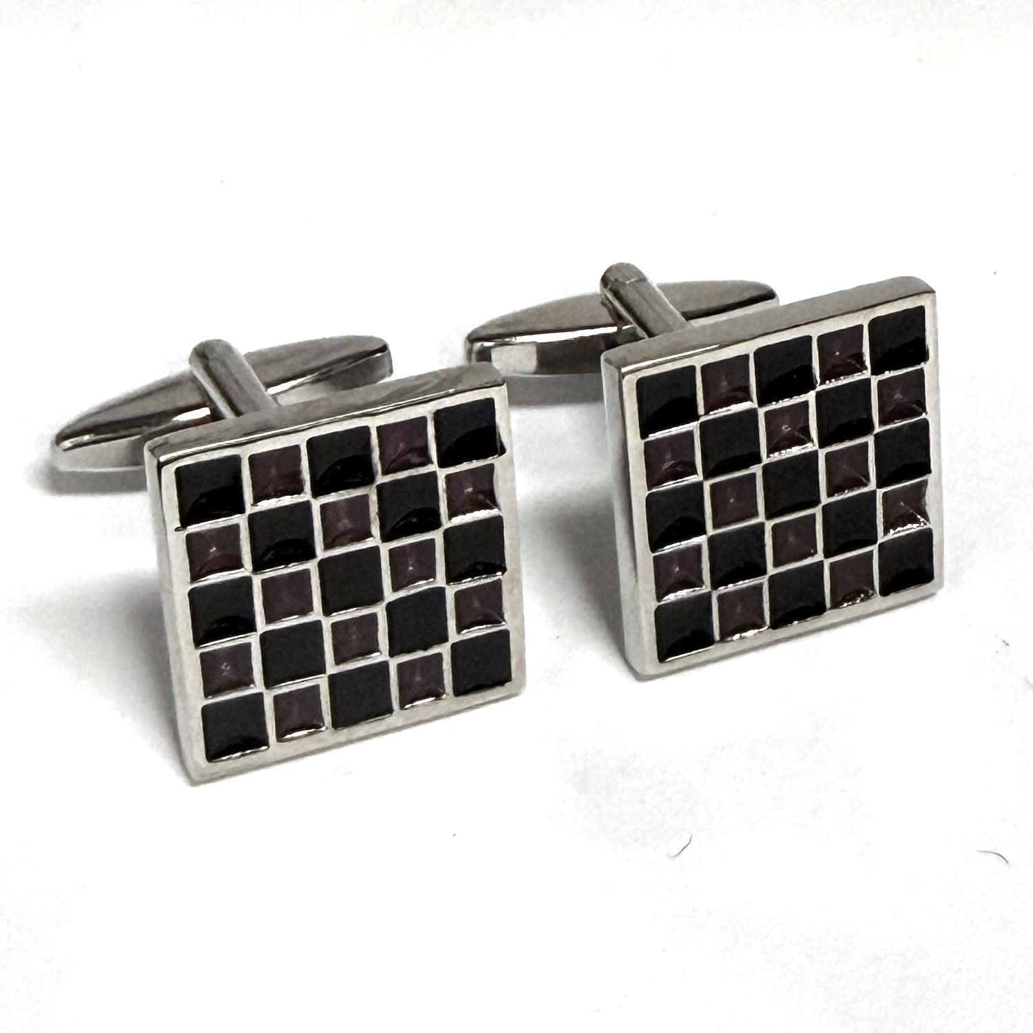 Pair of square cufflinks with black and silver checkered pattern on a white background